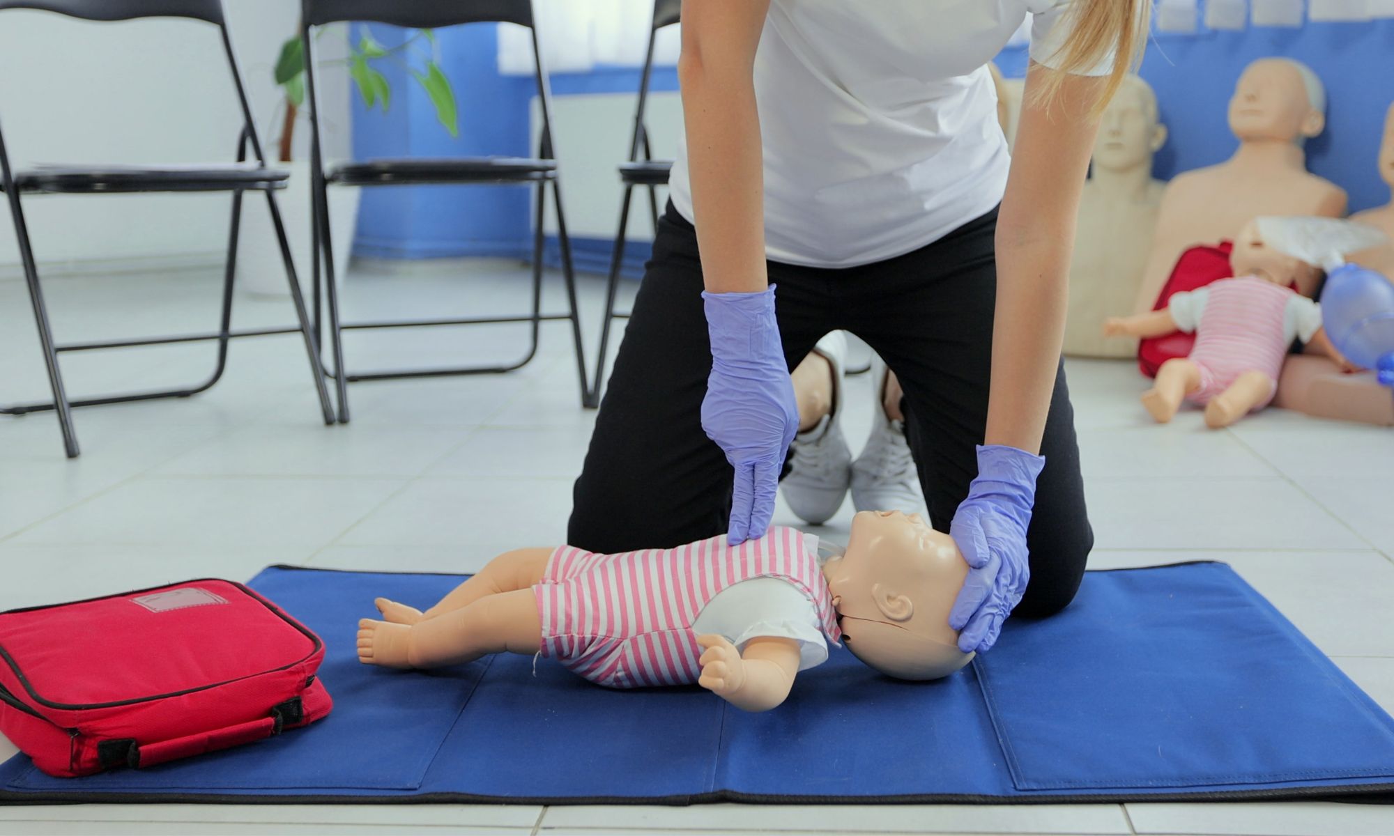A woman demonstrates Paediatric first aid on a dummy baby